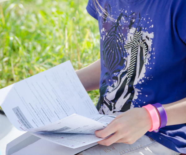 Ein Kind sitzt auf einer Wiese und liest in einem Heft.